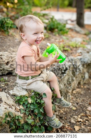 happy toddler boy drinks water sitting