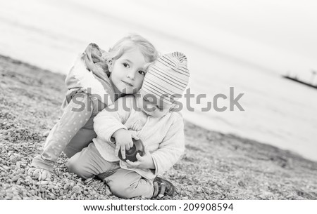 cute little brother and sister playing on the beach in spring time ( black and white )