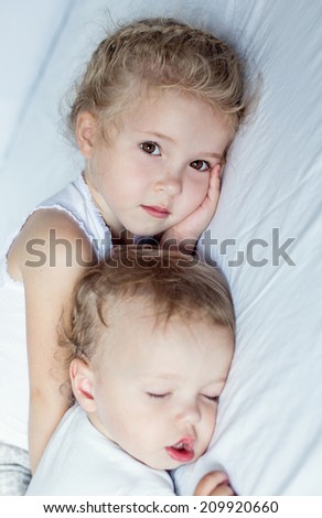 charming little brother and sister asleep on white background