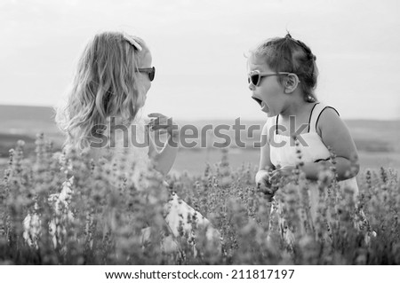 Two funny little girls play in a lavender field ( black and white )