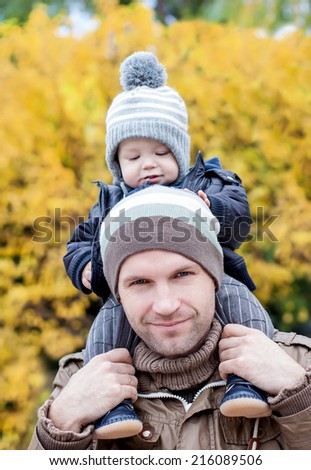 Happy father and his baby son having fun in the autumn park (soft focus on the father)
