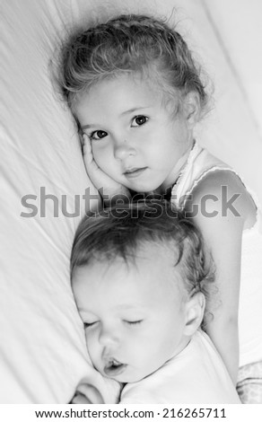 charming little brother and sister asleep on white background  ( black and white )