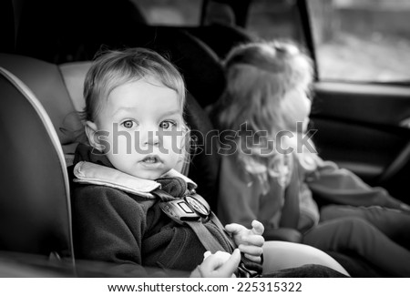 small children in car seats in the car ( black and white )