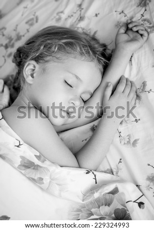 toddler girl is sleeping covered with a blanket ( black and white )