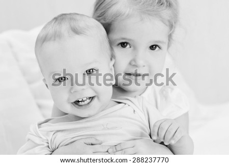 happy little sister hugging her brother ( black and white )