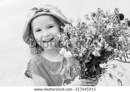 Happy toddler girl holding a bouquet of wildflowers ( black and white )