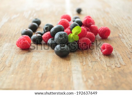 Blueberries and raspberries fruits pile on wooden table