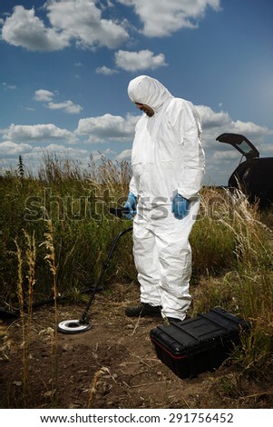 Criminologist technician exploring place with metal detector
