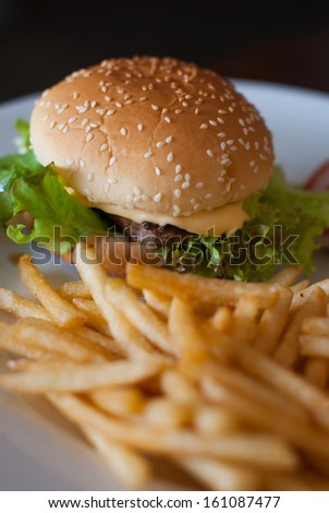 Cheeseburger And Fries with vegetables in white dish.