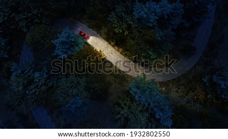Adventure night road trip in the forest, aerial view of a car headlights on deep jungle road. Mystery concept.