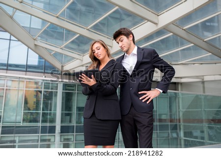 A young business couple standing in a modern buildings environment with a laptop computer