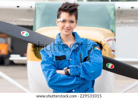 Ravenna, ITALY - Nov 9, 2014: One young beautiful woman pilot wearing Google Glass in front of a private airplane. Google Glass is a wearable head mounted android device produced by Google