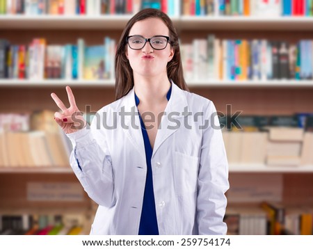 Portrait of young doctor with funny face showing a V as victory