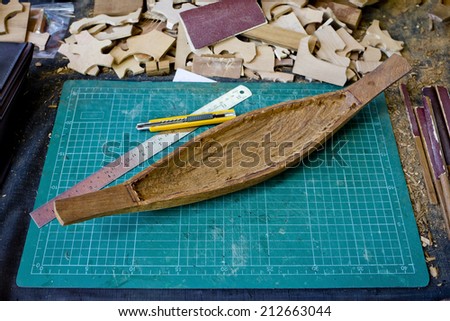 wooden scale model of a ship with tools set on table.