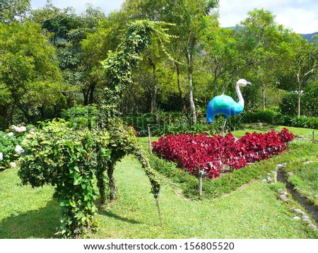 BOQUETE CHIRIQUI, PANAMA, DECEMBER 12 2006.  Trees, thick red bushes and sculptures of Flamingos in a flower garden in Boquete Chiriqui, Panama, on December 12 2006.