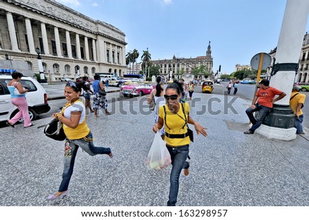HAVANA, CUBA, MAY 7, 2009. Two women in yellow shirts running on a street in Havana, in front of El Capitolio, in Havana, Cuba, on May 7th, 2009.