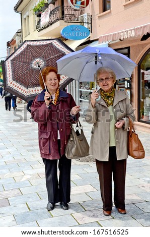 OHRID, MACEDONIA, MAY 17, 2011. Two stylish old women with umbrellas standing on the street smiling, in Ohrid, Macedonia, on May 17th, 2011.