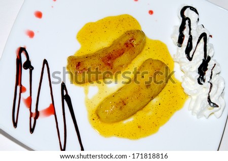 Oven cooked banana on a plate, with caramel, sauce,  and cream