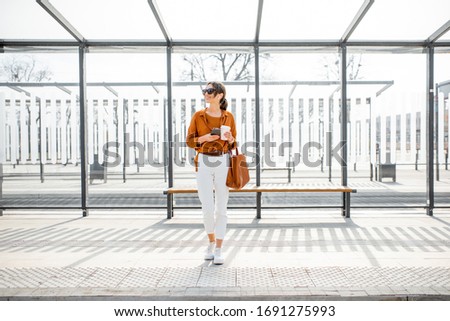 Woman standing alone at the public transport stop on a sunny day outdoors. Concept of a transportation and urban life 商業照片 © 