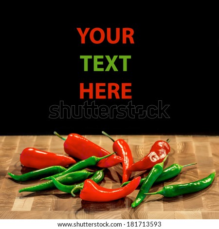 Hot red and green chili or chili pepper on wooden board and black background with space for text sample