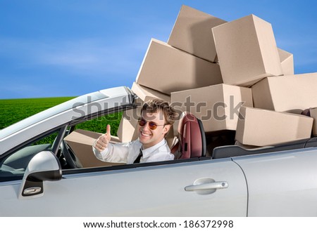 Smiling man in the car with baggage packed in boxes