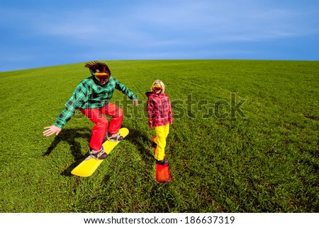 Young couple in sport wear snowboarding on the grass in the greenfield