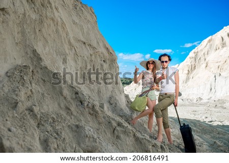 Young couple traveling on sandy locality with their baggage