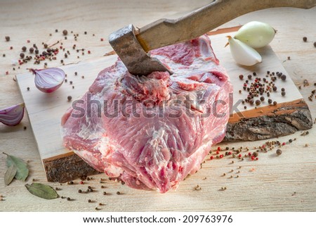 Raw meat decorated with spices and ax on wooden desk