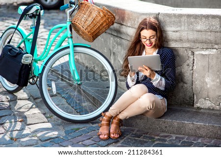Businesswoman going to work by bicycle speaking phone in old city center background