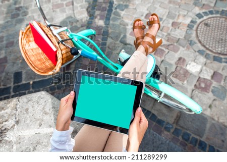 Holding tablet in the hands with bicycle on background in the city