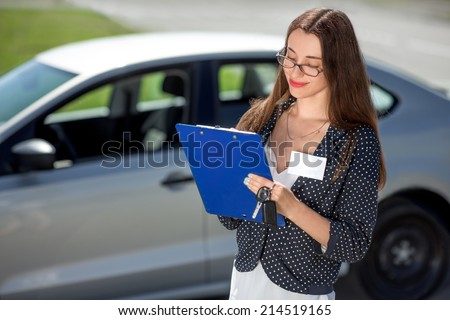 Young woman car rental inspector filling contract