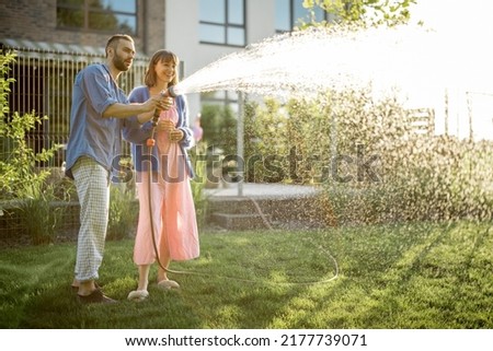 Similar – Image, Stock Photo Watering the lawn with water in summer. gardening concept. drops of water from the ameliorative irrigation system are fed to grow ing garden plants against a sunny day