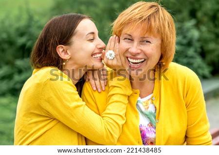 Daughter whispering something to her mother in the park