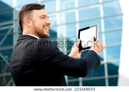 Businessman taking photo of contemporary building with digital tablet