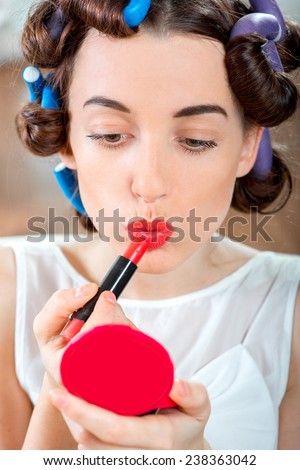 Smiling woman with hair curlers using red lipstick