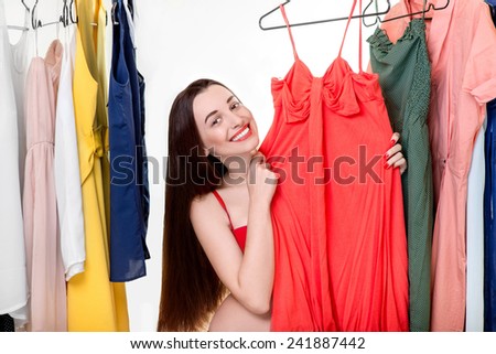 Young happy woman dressed in underwear choosing dress to wear in the wardrobe