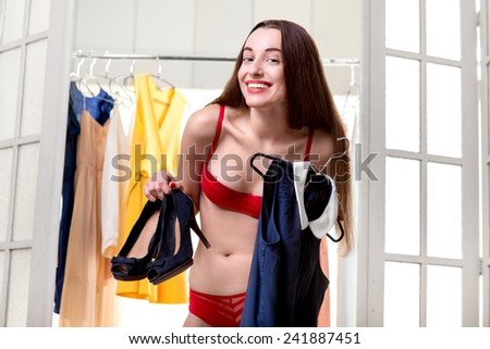 Young happy woman trying on new blue dress and shoes to wear in the wardrobe