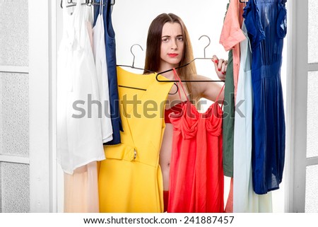 Young happy woman trying on new dress to wear in the wardrobe