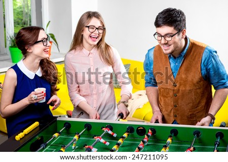Young friends or students having fun together playing table football