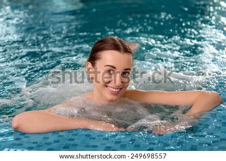 Young woman enjoying jacuzzi in the swimming pool at the hotel spa