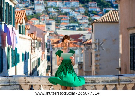 Young woman in green dress using digital tablet in Dubrovnik old city center
