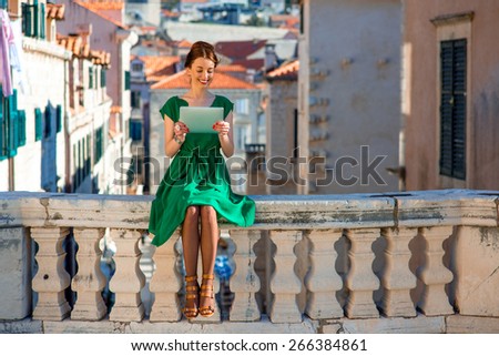 Young woman in green dress using digital tablet in Dubrovnik old city center