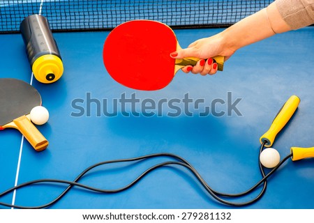 Holding table tennis racket with balls, rope and drink bottle on a blue table on background