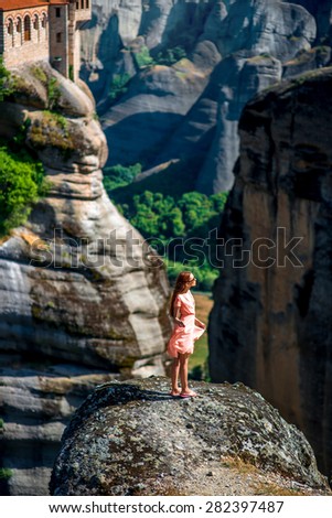 Young woman in pink dress enjoying nature on the mountains near Meteora monasteries in Greece