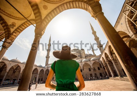 Young woman traveler in black hat and green dress looking on amazing Blue Mosque in Istanbul, Turkey