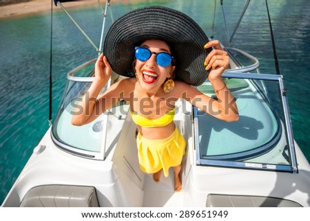 Young playful woman with big hat and sunglasses having fun on the yacht. Happy summer vacation. Top view with wide angle