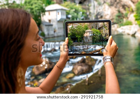 Female tourist photographing with digital tablet house on Buna spring in Blagaj village in Bosnia and Herzegovina
