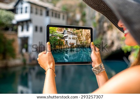 Female tourist photographing with digital tablet house on Buna spring in Blagaj village in Bosnia and Herzegovina