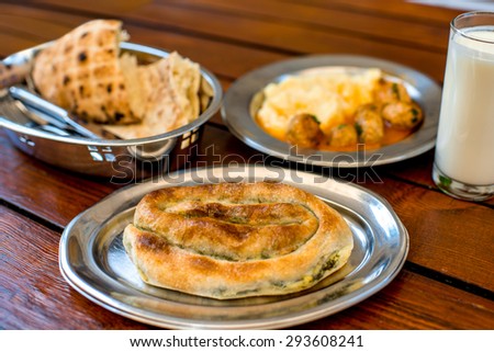 Burek with bread, potato and meat balls in metal plates on wooden table. Traditional balkan\'s food