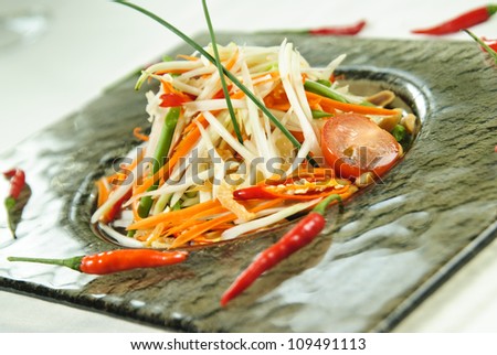 Plate of Thai salad arranged with red chilly peppers.
